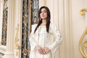 Woman in a white embroidered outfit standing in an ornate interior setting